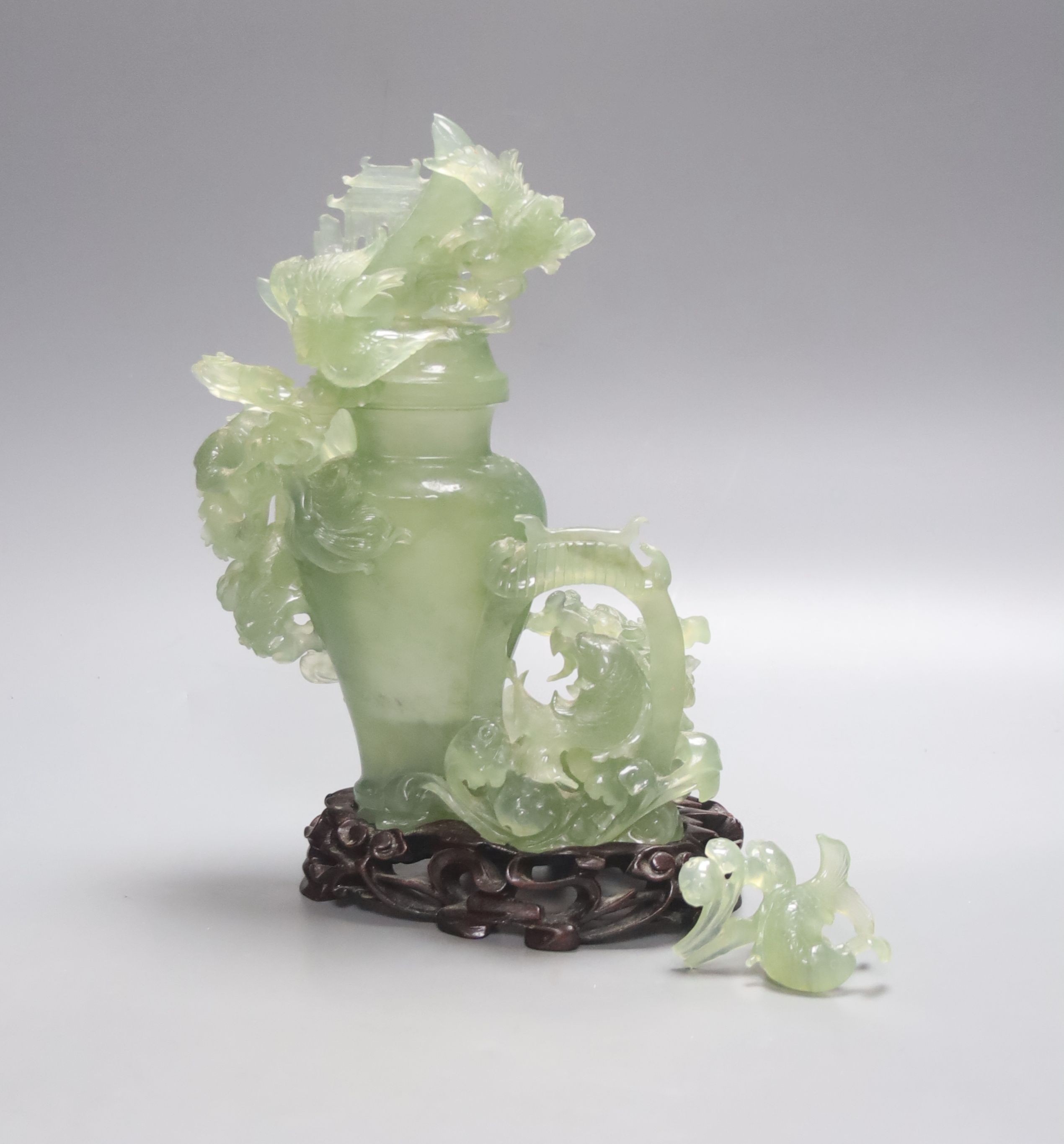 A Chinese green bowenite jade group modelled as a covered urn surrounded by a dragon, H 26cm with carved stand